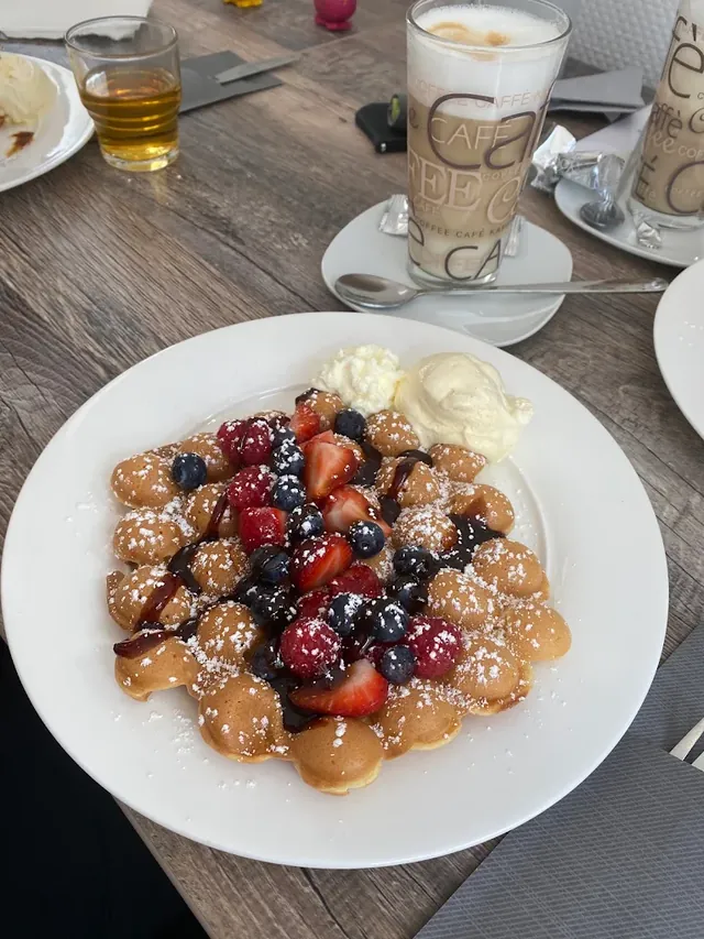Bubble Waffle mit Erdbeeren, Himbeeren und Heidelbeeren, dazu Eis und Latte macchiato