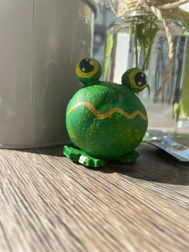 Bemalter grüner Holzfrosch auf einem Tisch im Quak Café