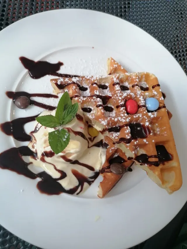 Waffel mit Vanilleeis, Schokoladensoße, Puderzucker und Minze