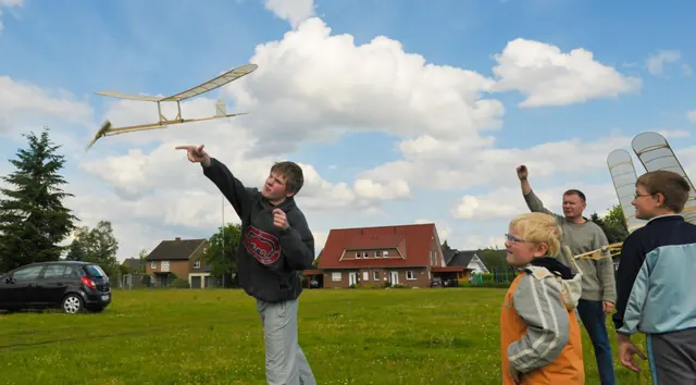 Schüler lassen ihre selbstgebauten Segelflugmodelle auf einer Wiese fliegen