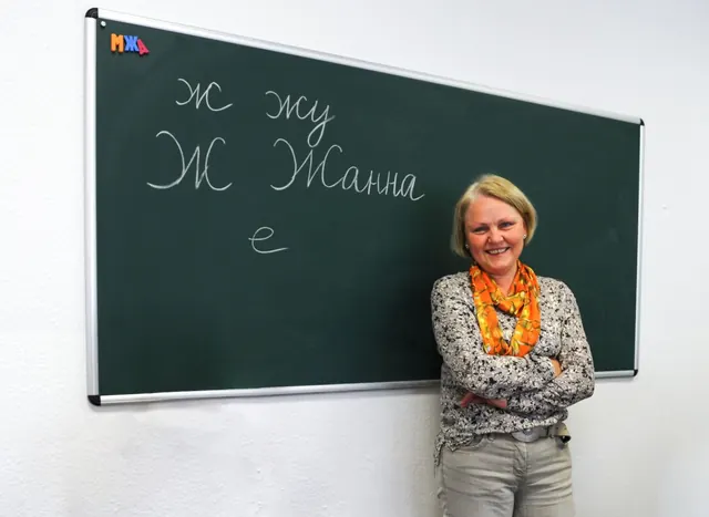 Lehrerin an der Tafel mit kyrillischen Buchstaben im Russischunterricht